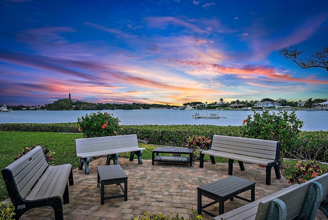 patio terrace at dusk featuring a water view