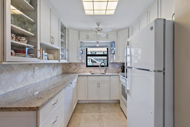 kitchen featuring light stone countertops, backsplash, white appliances, sink, and white cabinets