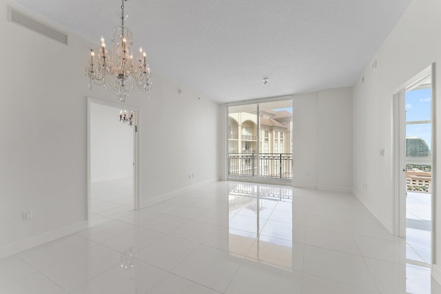 empty room featuring light tile patterned flooring, a textured ceiling, and a notable chandelier