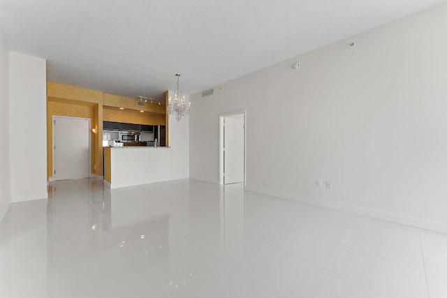 unfurnished living room with light tile patterned flooring, a textured ceiling, and an inviting chandelier