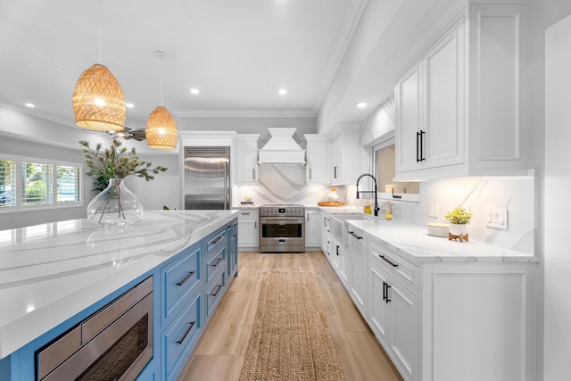 kitchen with built in appliances, light stone counters, white cabinets, and premium range hood