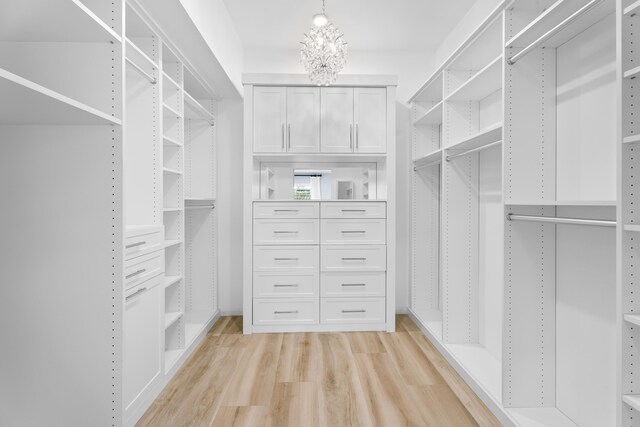 walk in closet with light hardwood / wood-style floors and a notable chandelier