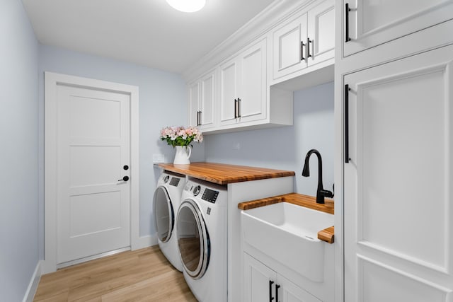 washroom with cabinets, washer and dryer, sink, and light wood-type flooring