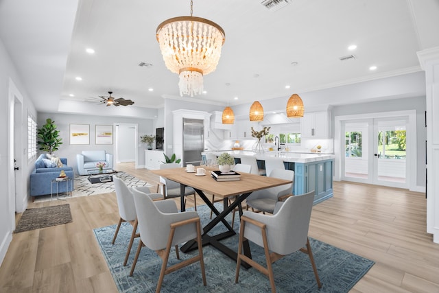 dining space featuring crown molding, ceiling fan with notable chandelier, sink, and light hardwood / wood-style flooring