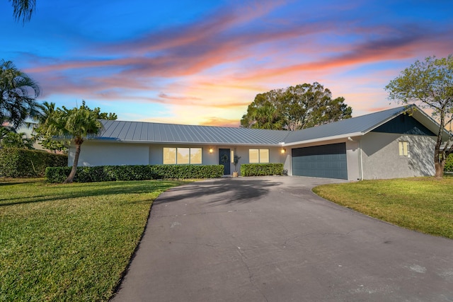 single story home featuring a garage and a yard