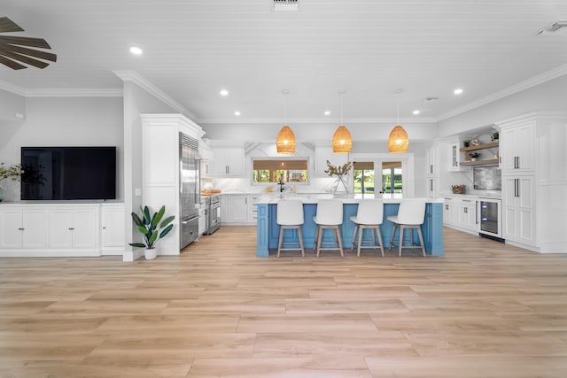 kitchen with pendant lighting, a center island, white cabinets, a kitchen bar, and beverage cooler