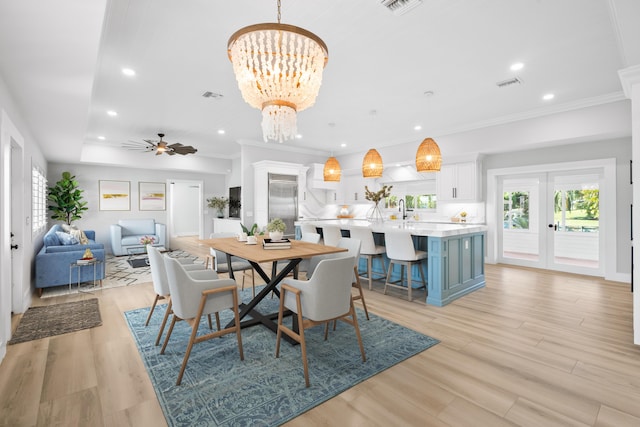 dining room featuring ceiling fan with notable chandelier, ornamental molding, light hardwood / wood-style floors, and french doors