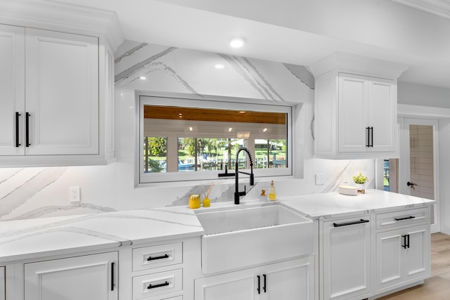 kitchen featuring light stone countertops, sink, and white cabinets