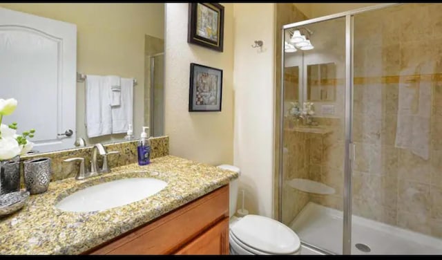 bathroom featuring vanity, an enclosed shower, and toilet