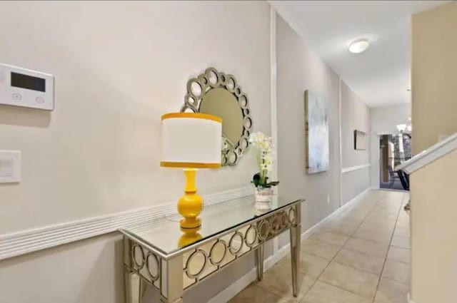 hall featuring light tile patterned flooring and a chandelier