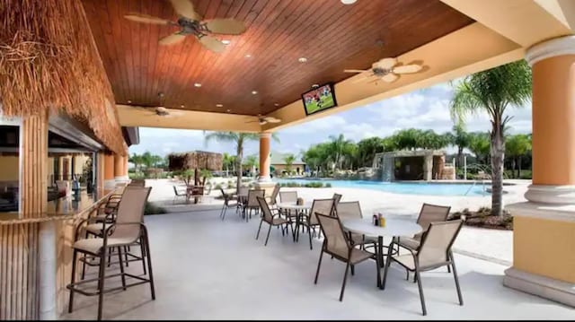 view of pool with ceiling fan, an outdoor bar, and a patio