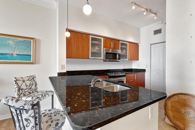 kitchen with sink, hanging light fixtures, stainless steel appliances, kitchen peninsula, and a textured ceiling