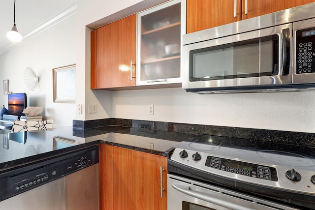 kitchen featuring pendant lighting, crown molding, dark stone countertops, and stainless steel appliances