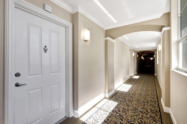 corridor with crown molding and dark colored carpet