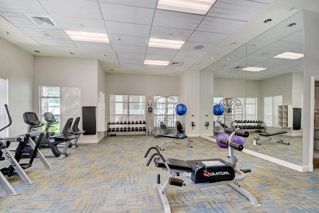 gym featuring carpet, a drop ceiling, and a towering ceiling