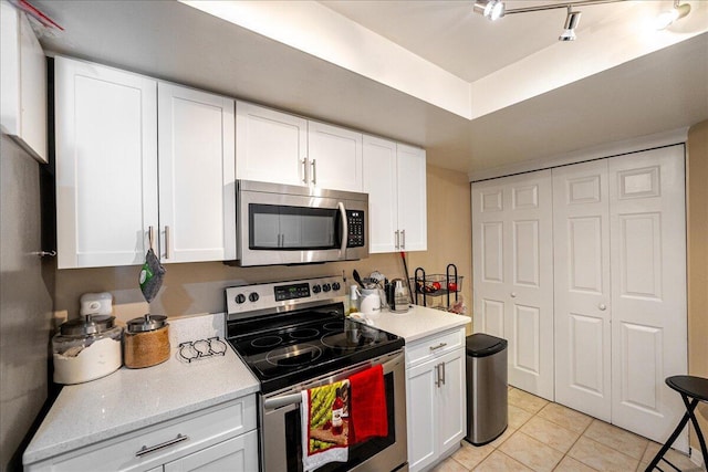 kitchen with white cabinetry, light tile patterned floors, track lighting, and appliances with stainless steel finishes