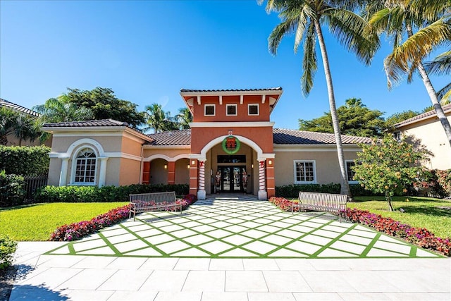 mediterranean / spanish-style house featuring french doors and a front lawn