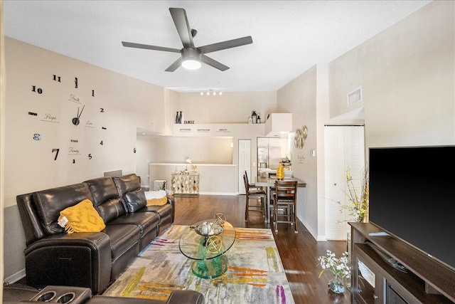 living room with a textured ceiling, dark hardwood / wood-style flooring, and ceiling fan