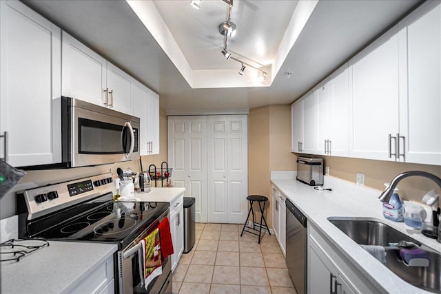 kitchen with white cabinetry, sink, rail lighting, stainless steel appliances, and light tile patterned flooring