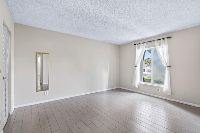 empty room with hardwood / wood-style floors and a textured ceiling