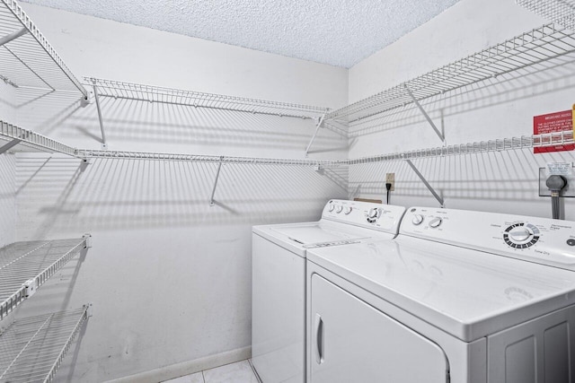 washroom with washer and clothes dryer and a textured ceiling