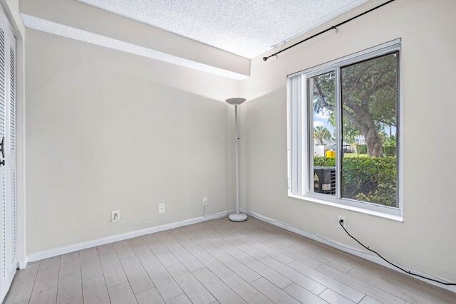 unfurnished room featuring a textured ceiling and light wood-type flooring