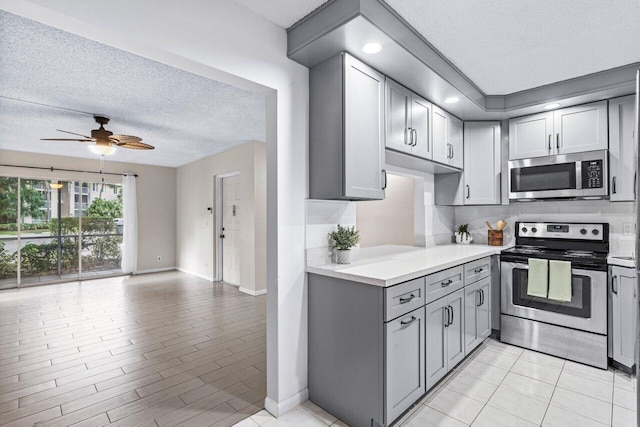 kitchen with a textured ceiling, stainless steel appliances, and gray cabinets