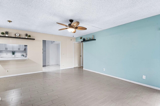 spare room featuring a textured ceiling, light hardwood / wood-style floors, and ceiling fan