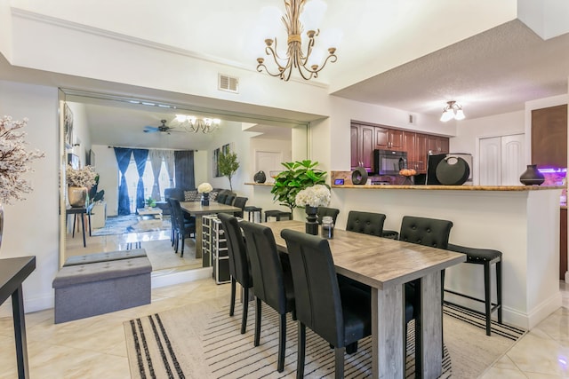 tiled dining room featuring a textured ceiling and ceiling fan with notable chandelier