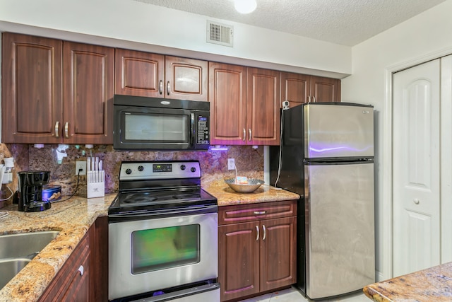 kitchen featuring light stone countertops, tasteful backsplash, a textured ceiling, stainless steel appliances, and sink