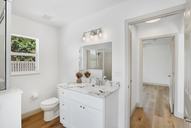 bathroom featuring hardwood / wood-style floors, vanity, toilet, and a shower with door