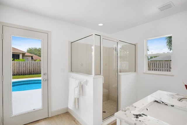 bathroom featuring vanity, hardwood / wood-style flooring, and a shower with door