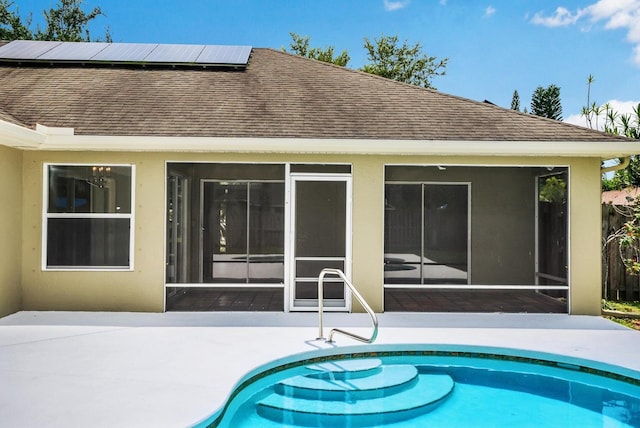 rear view of property featuring a sunroom, solar panels, and a patio area