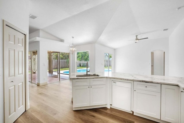 kitchen with white cabinetry, dishwasher, sink, lofted ceiling, and light wood-type flooring