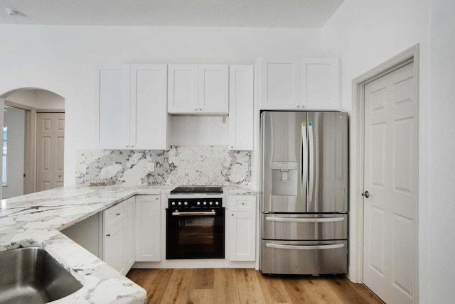 kitchen with stainless steel refrigerator with ice dispenser, electric range, light stone countertops, light wood-type flooring, and white cabinetry