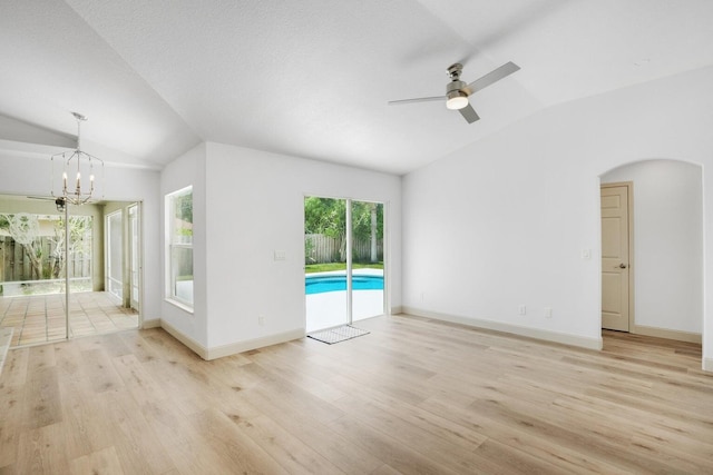 unfurnished room featuring ceiling fan with notable chandelier, vaulted ceiling, and light wood-type flooring