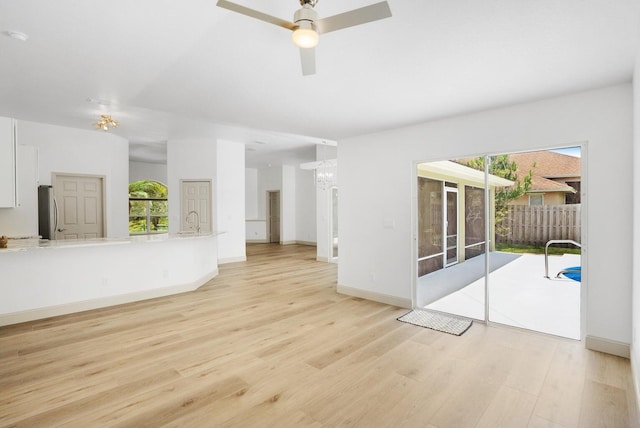 unfurnished living room featuring sink, light wood-type flooring, plenty of natural light, and ceiling fan