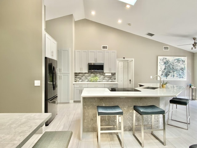 kitchen with white cabinetry, sink, a breakfast bar area, a center island with sink, and appliances with stainless steel finishes