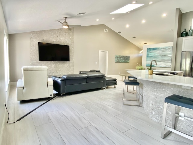 living room featuring ceiling fan, light hardwood / wood-style floors, lofted ceiling, and sink