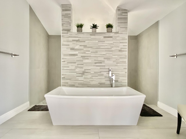 bathroom with a tub to relax in, tile walls, and lofted ceiling