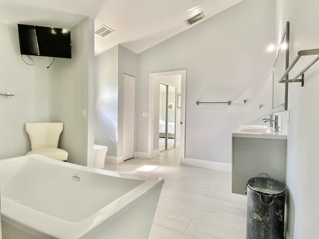 bathroom with vanity, a tub to relax in, and vaulted ceiling