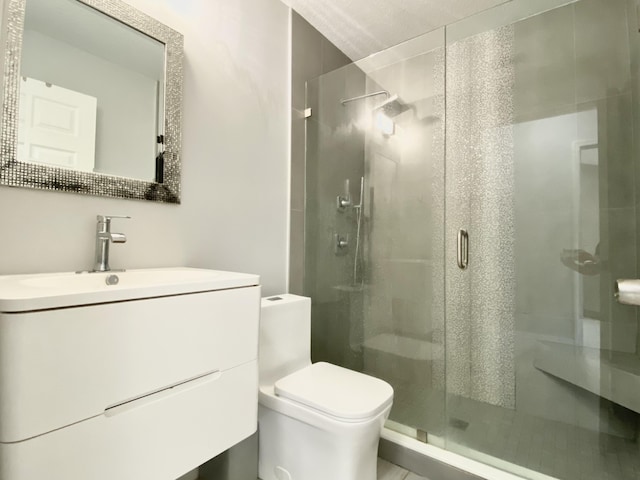 bathroom featuring vanity, a shower with shower door, and toilet