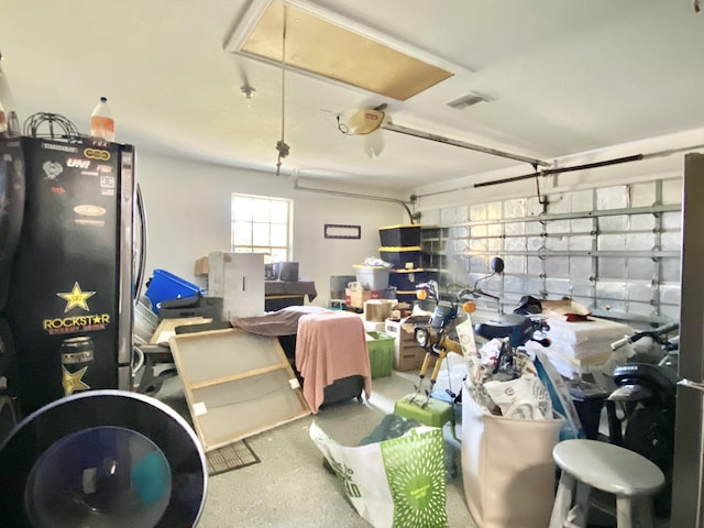 garage with stainless steel fridge and a garage door opener