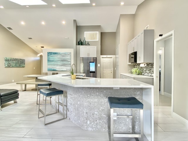 kitchen featuring stainless steel fridge with ice dispenser, white cabinetry, sink, and a spacious island