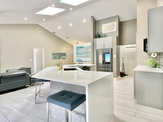 kitchen featuring a skylight, a breakfast bar, a spacious island, sink, and stainless steel refrigerator