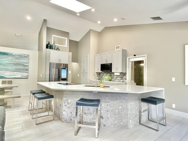 kitchen with white cabinets, stainless steel refrigerator with ice dispenser, a large island, and sink