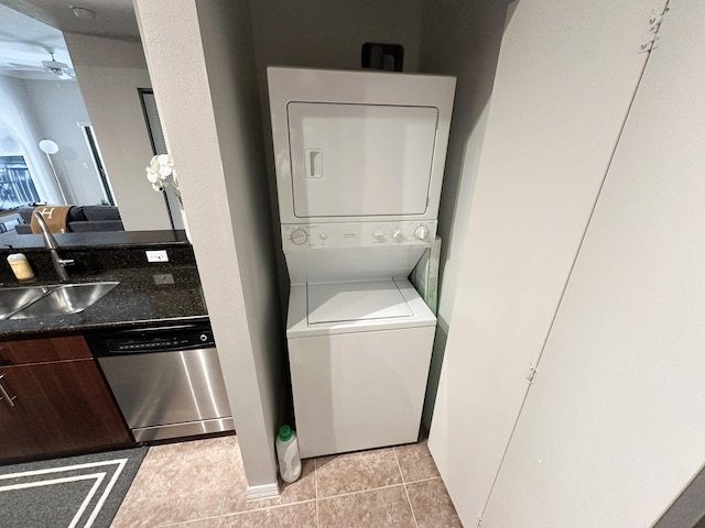 laundry room featuring light tile patterned floors, ceiling fan, stacked washer / drying machine, and sink