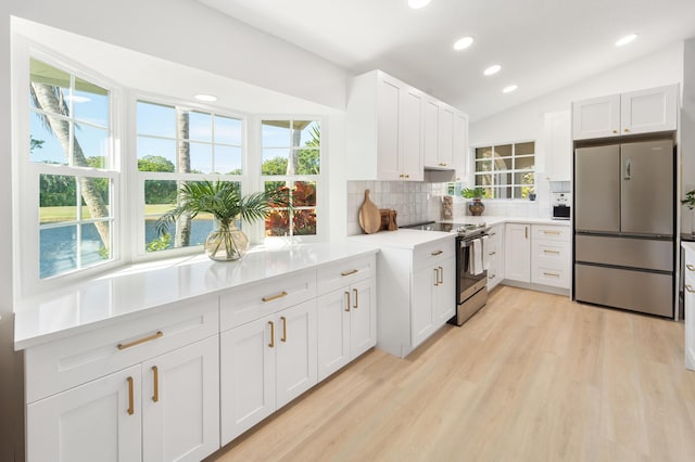 kitchen with white cabinets, appliances with stainless steel finishes, decorative backsplash, and vaulted ceiling