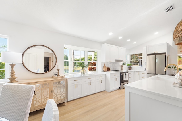 kitchen with white cabinets, plenty of natural light, stainless steel appliances, and vaulted ceiling