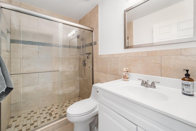 bathroom featuring vanity, a shower with door, toilet, and tile walls